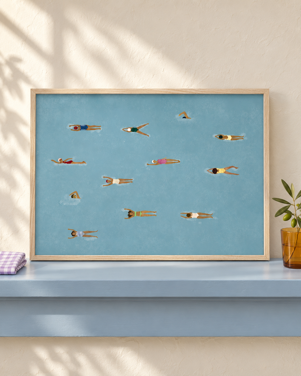 Beneath The Surface blue swimmers art in an oak frame on a powder-blue shelf; lifestyle visualisation