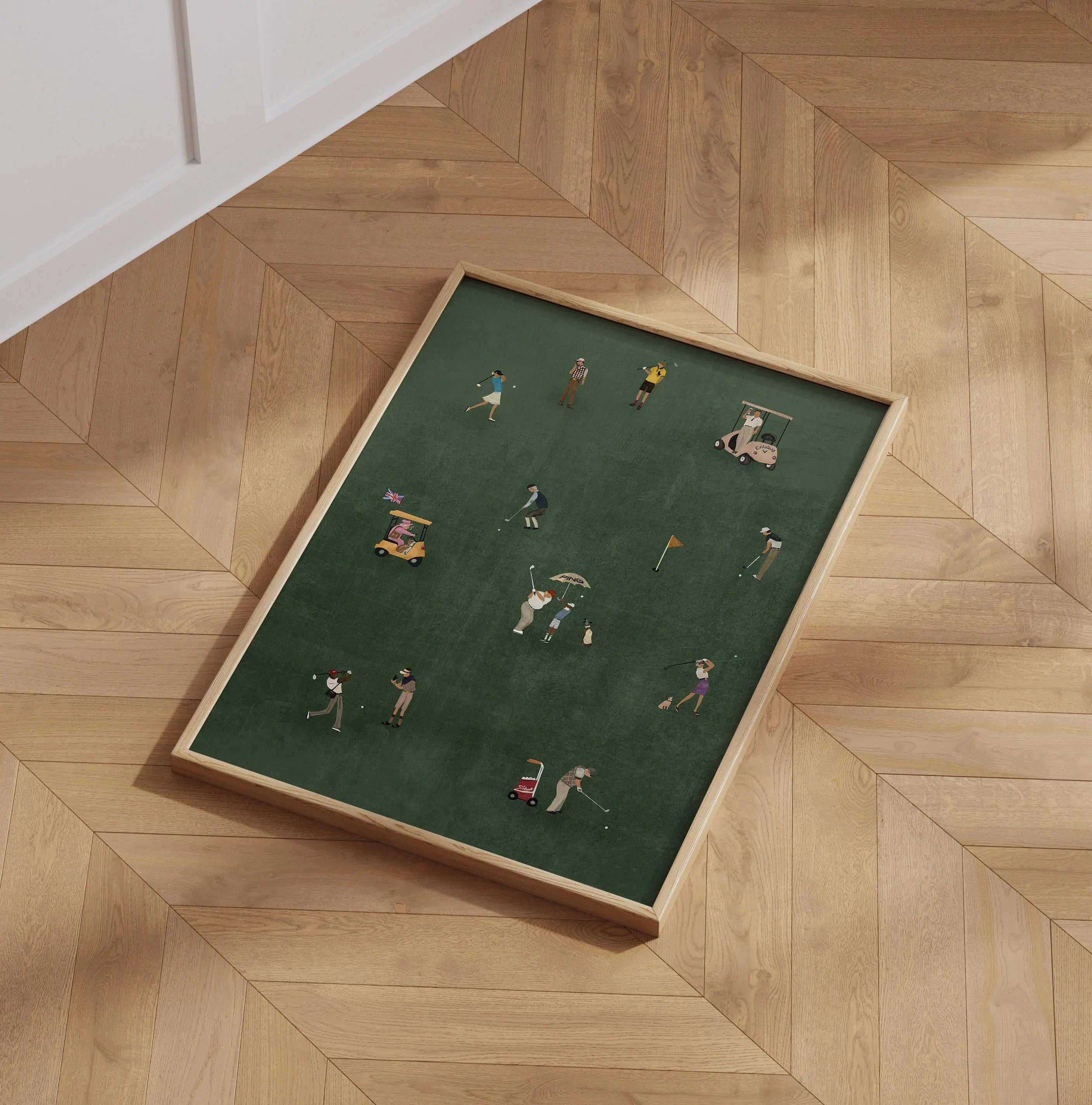 Framed artwork of miniature golfers on a green background, displayed on a wooden floor.