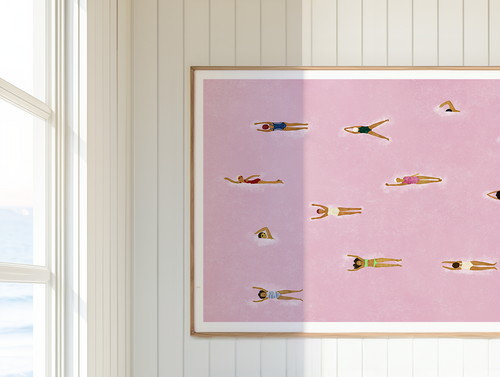 The Red Sea pink swimming art print framed on a white panelled wall.