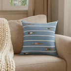 Blue swimming lanes Beach Day Pillow styled in a beige armchair beside a knitted throw.