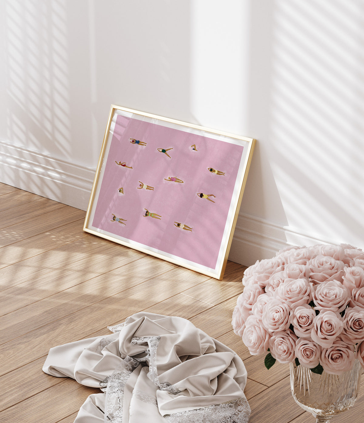 Pink swimming art print styled beside flowers in a sunlit room.
