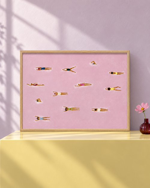 The Red Sea pink swimmers art in an oak frame on a butter-yellow console; lifestyle visualisation